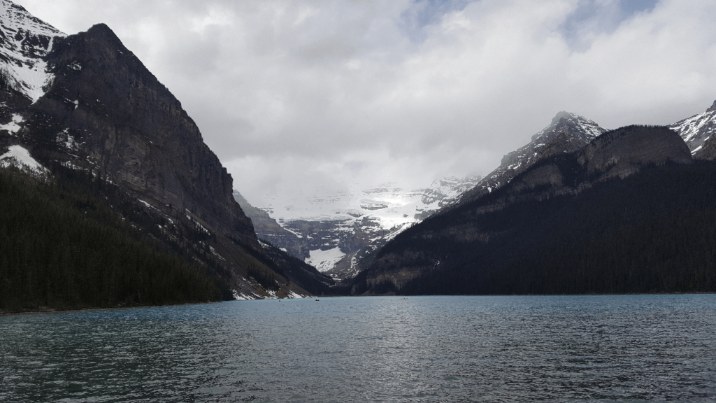 mountain lake with steep mountains around and a glacier at the back of the valley