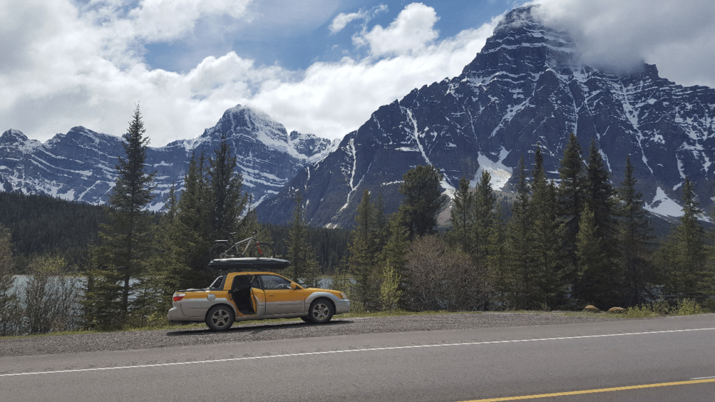 parked on the side of the road with snowy mountains behind