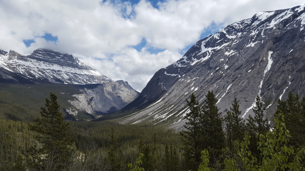 looking down a glacially carved valley with snow in the mountians