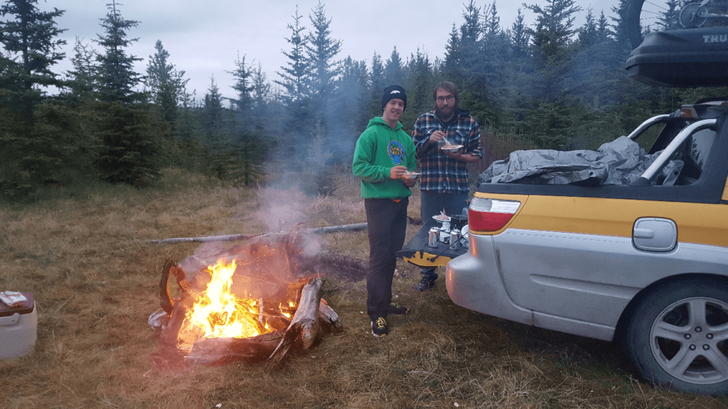 camping behind a subaru baja in a grassy meadow 
