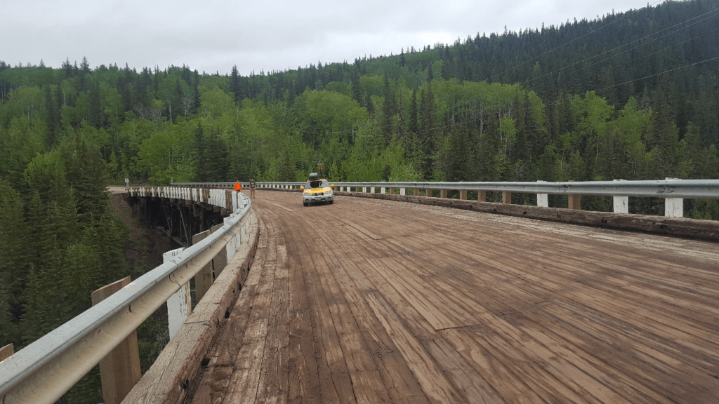 Wide curved wooden bridge with a subaru baja parked on it