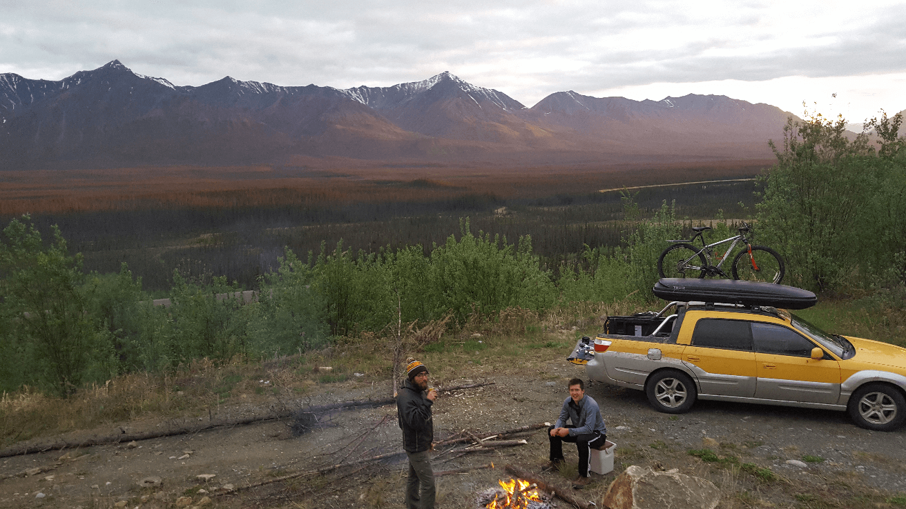 drinking around a campfire with sunset on the mountains behind