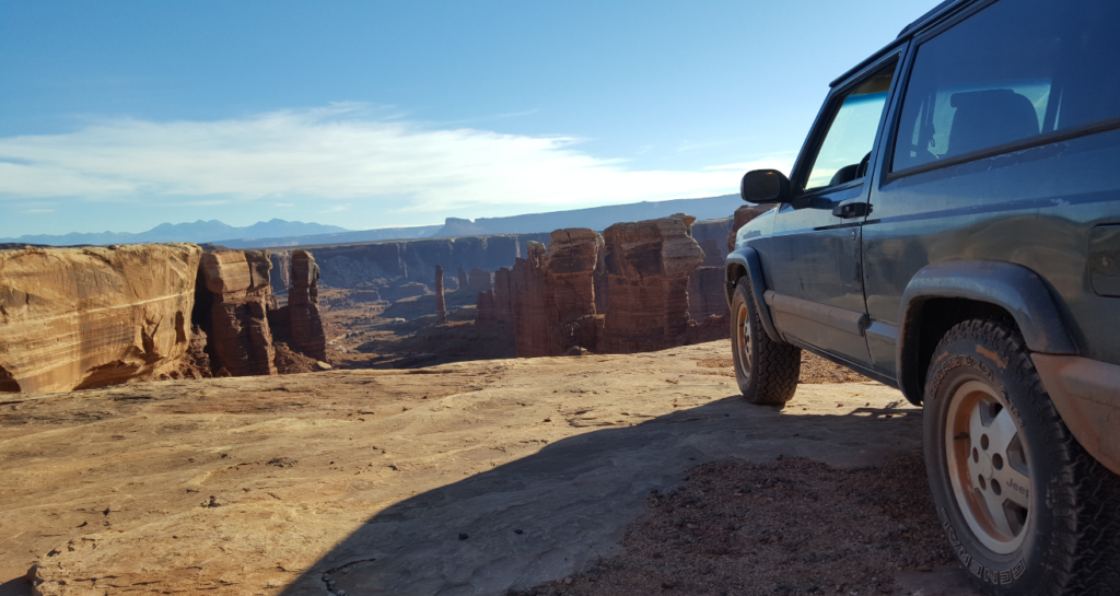 jeep overlooking desert towers in canyon