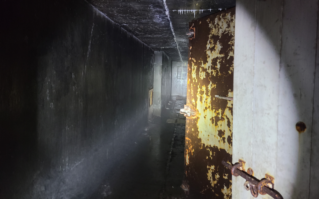 dark concrete hallway with metal doors