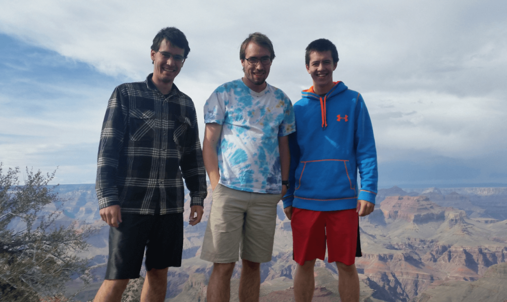 three amigos standing in front of a grand canyon viewpoint