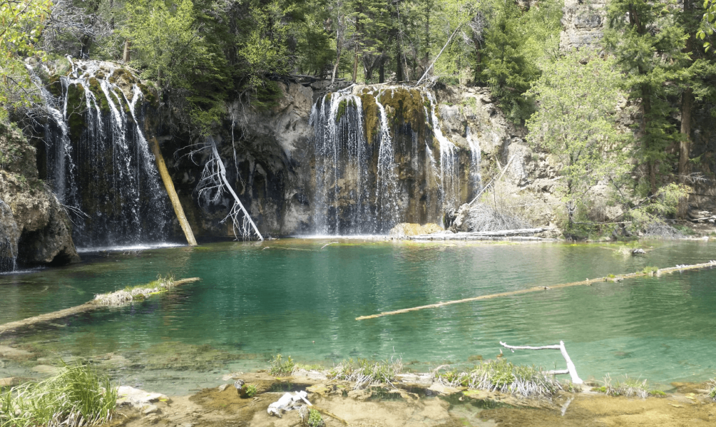 clear green lake with mossy waterfalls behind