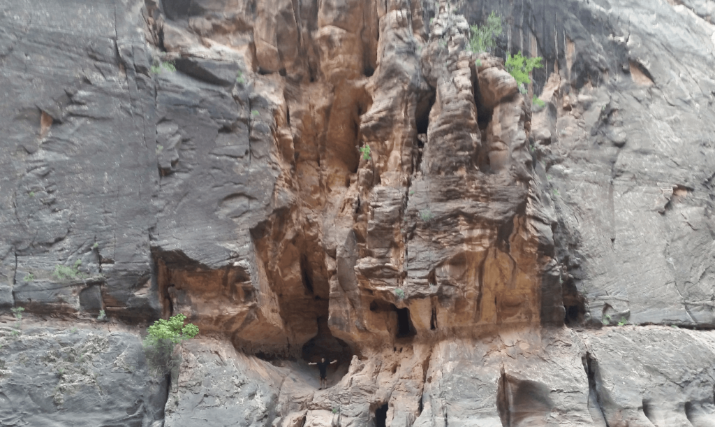 joseph standing in a giant sandstone alcove in the canyon wall