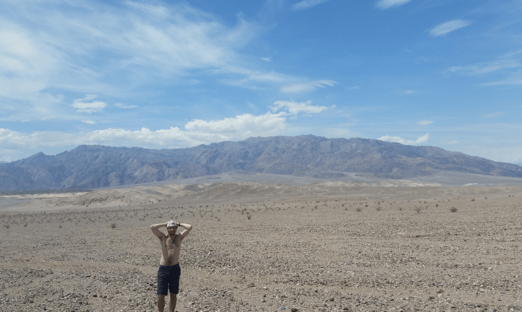 mike with his hands over his head in a stark desert landscape