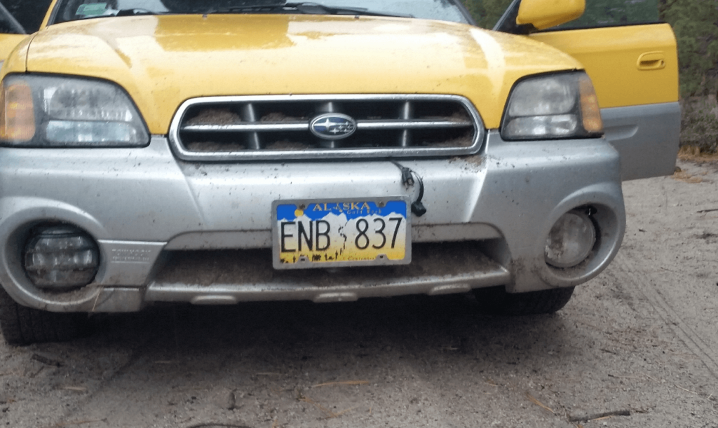 the front end of a subaru baja with sand in the air intake, radiator, and headlights