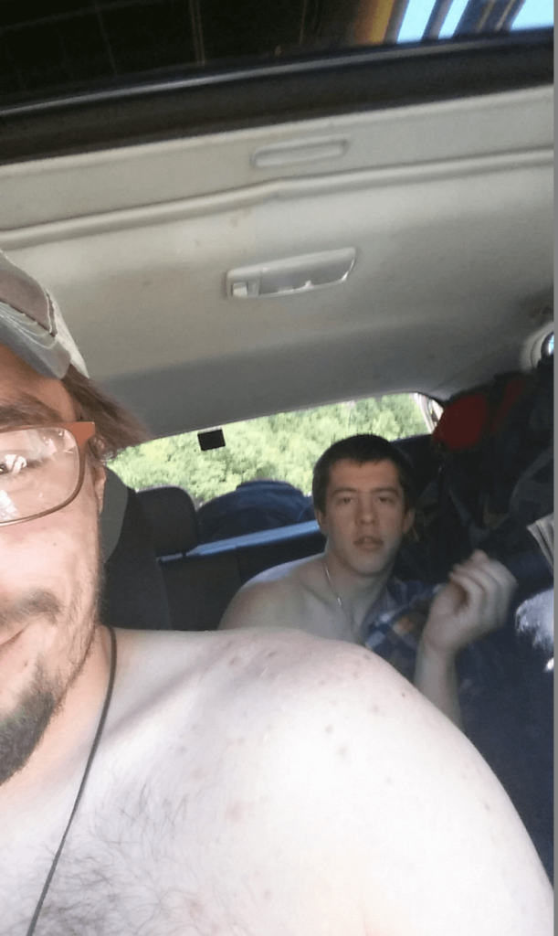 mike and joseph shirtless in a car goofing off