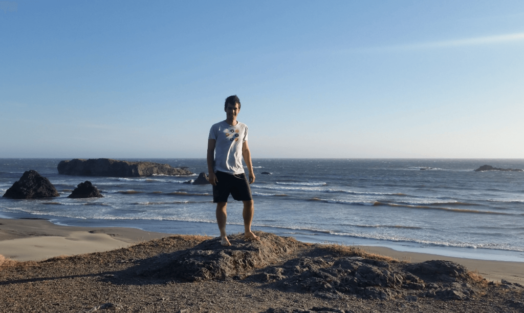 robert standing in front of the oregon coast with seamounts and waves behind