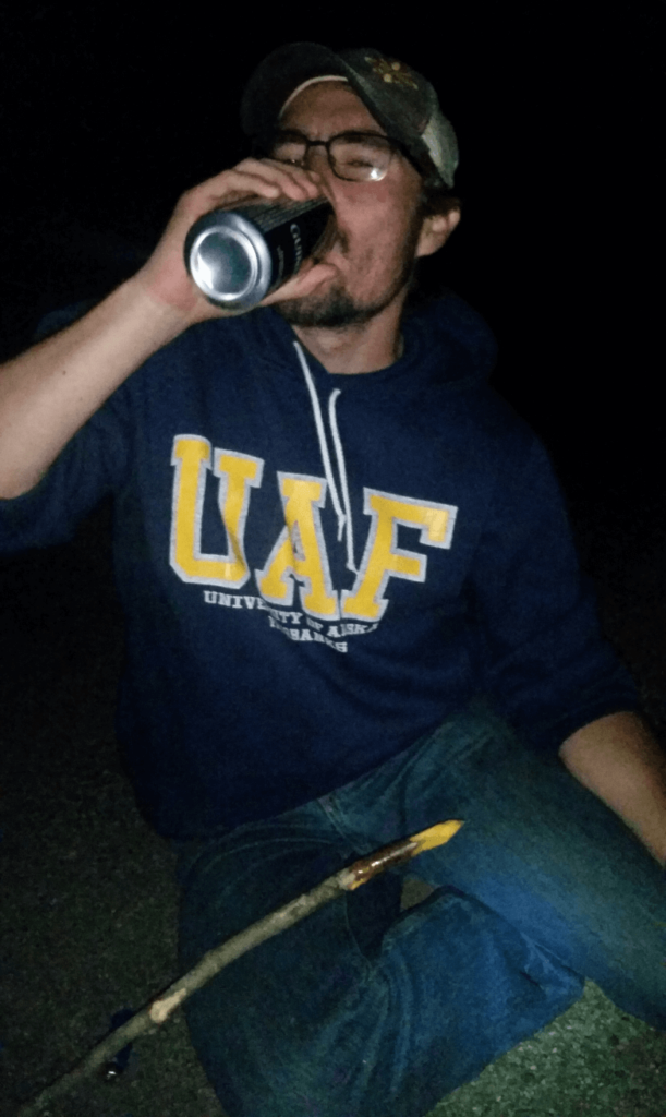 mike drinking a beer late at night crouching in the gravel