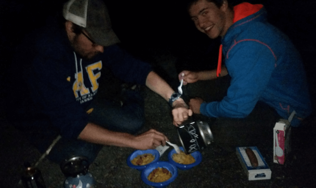 mike and joseph portioning out mac n cheese in a gravel pit
