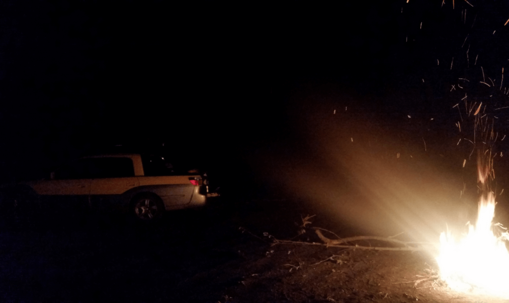 campfire in a gravel pit with the baja in the dark behind